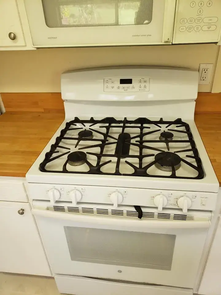 White kitchen stove with gas burners and oven.
