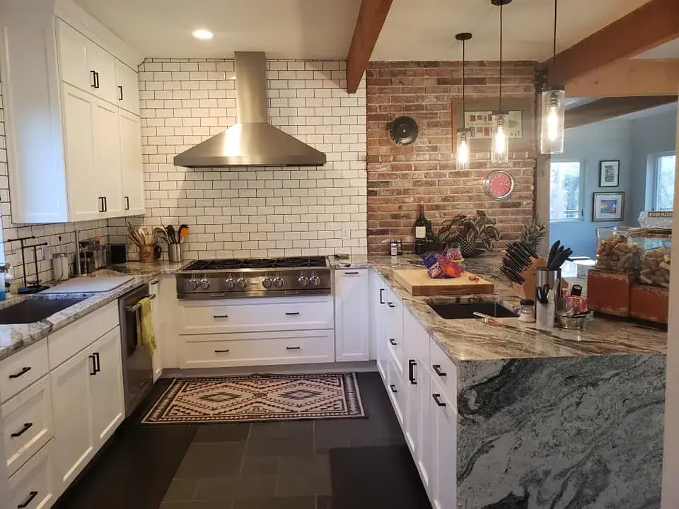 Modern kitchen with white cabinets and brick wall.