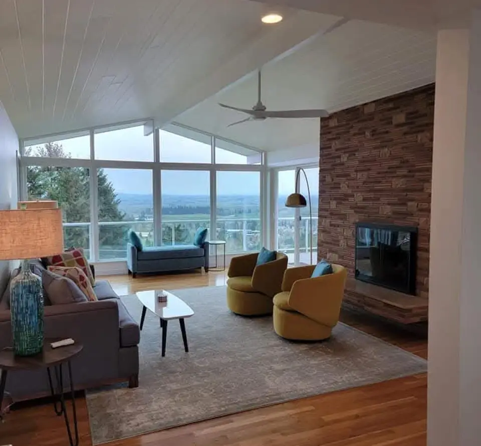 Modern living room with large windows and fireplace.